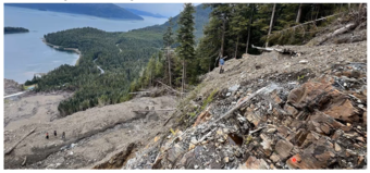 steep slope covered with rocks and trees with water in background