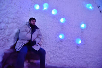 person with coat on sitting down with snow all around