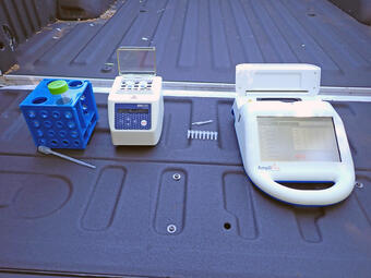 several pieces of a portable DNA rapid test kit placed on the lowered tailgate of a pickup truck