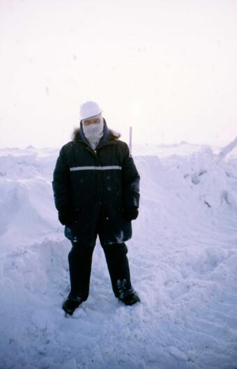 Man standing in front of a snowy backdrop wearing heavy winter gear.