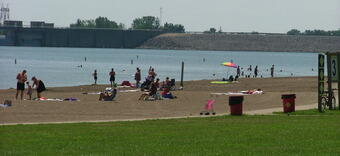 Blue lake up against a sand beach with families on it.