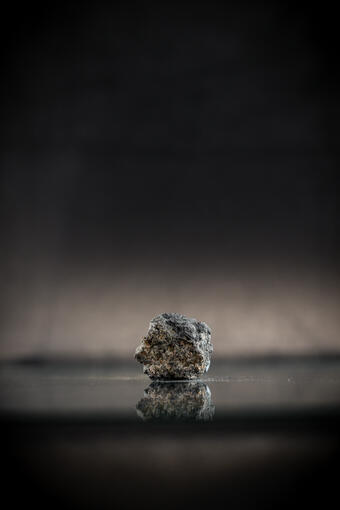 Isolated lump captured in high-definition photography, emphasizing flaky texture and dark gray color.