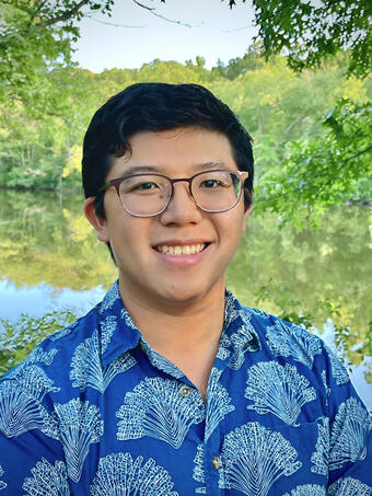 Color photograph of male with aloha shirt on and greenery in the background