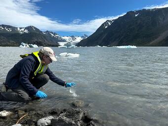 Scientist takes a water sample from a glacial lake in Alaska