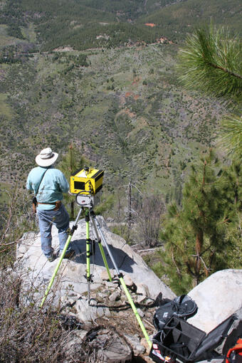 A person looking across the valley using a laser scanning the entire Cleveland Corral landslide.