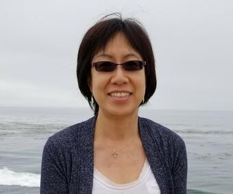 Woman with short hair standing in front of the ocean