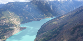 Blue lake between two mountains with white outline around landslide