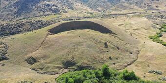 hillslope covered with grass and trees. landslide is visible on hillslope