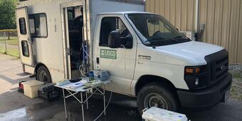 A white USGS van, with water quality sampling supplies inside, provides a mobile laboratory for USGS staff.