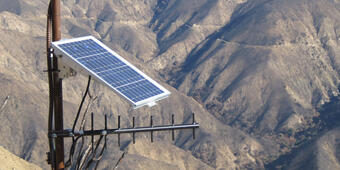 Solar panels, wires, and other equipment on a hillside devoid of vegetation.  