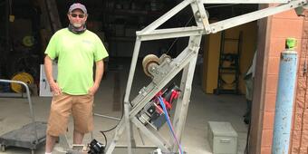 man in usgs shirt standing next to a variable rate sediment sampler