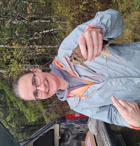 Sarah Clements staff profile picture. Woman in blue jacket holding bird.