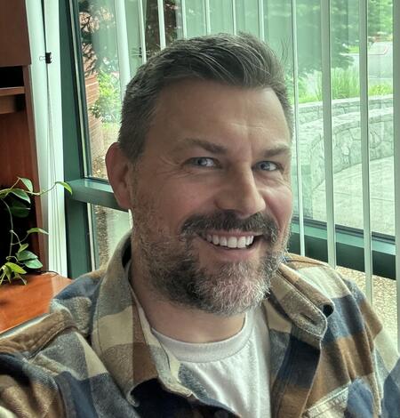 staff profile showing a man smiling in front of a window