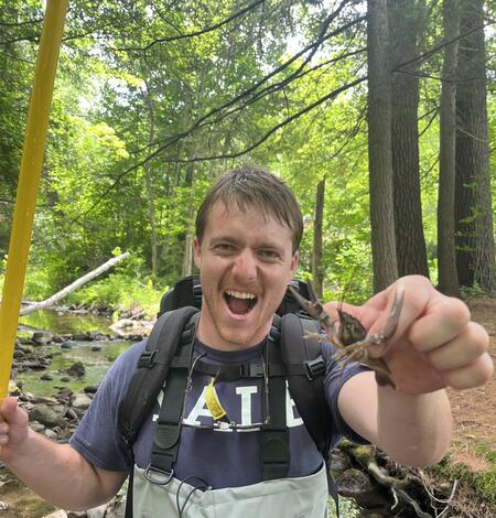 Man in waders holding a crayfish in the foreset