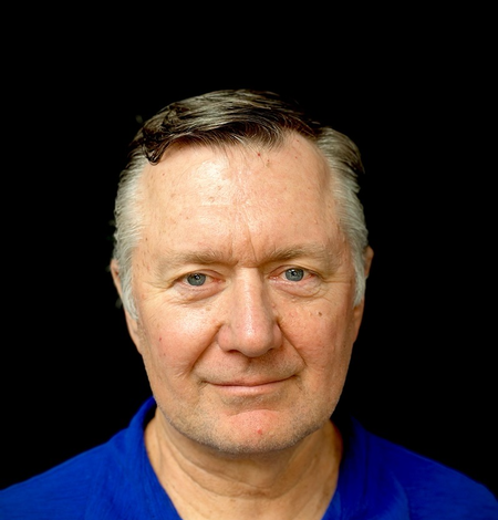 man with blue eyes wearing a blue shirt with a black background