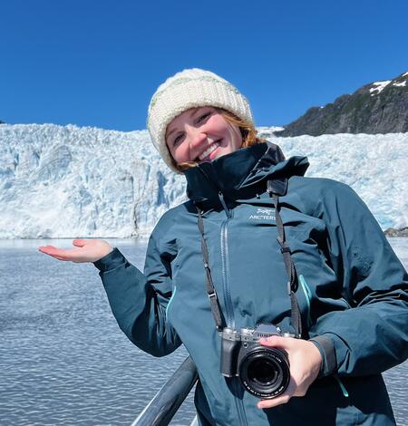 Ellie Miller standing on deck of a boat in front of a glacier