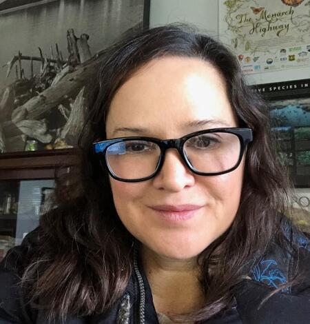 Headshot of a woman with long dark hair wearing glasses with a thick black frame