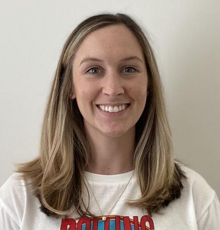 Head shot of a female with shoulder length brown hair and brown eyes wearing a white sweater.