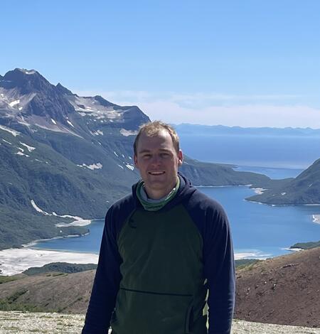 white man in front of a mountain and lake