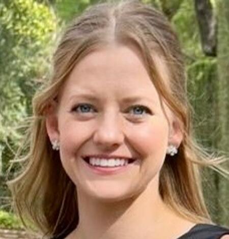 blonde-haired woman smiling wearing black shirt with plants in the background