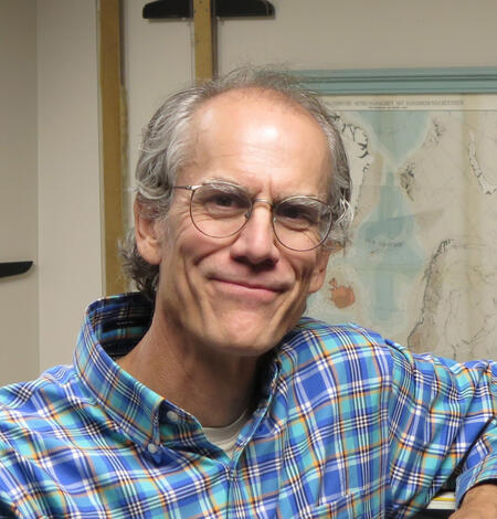 Jeremy Havens standing in front of the office T-square collection, which hang from the wall