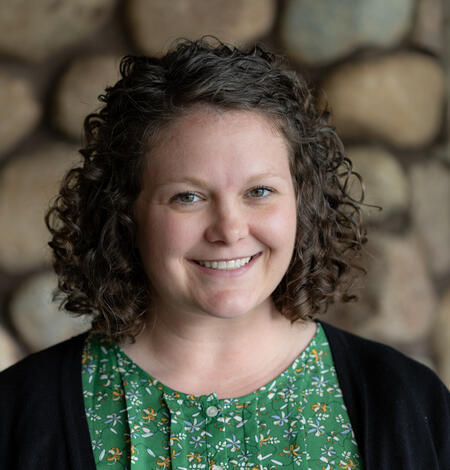 smiling woman standing against a stone backdrop