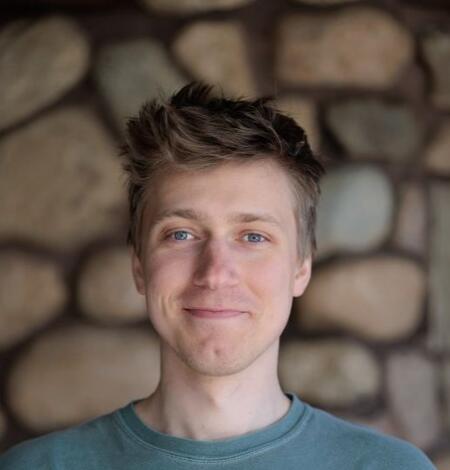 Man smiling while standing in front of stone wall background