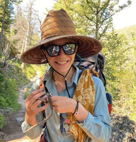 biologist Kristina Parker with a snake around their neck and large hat on