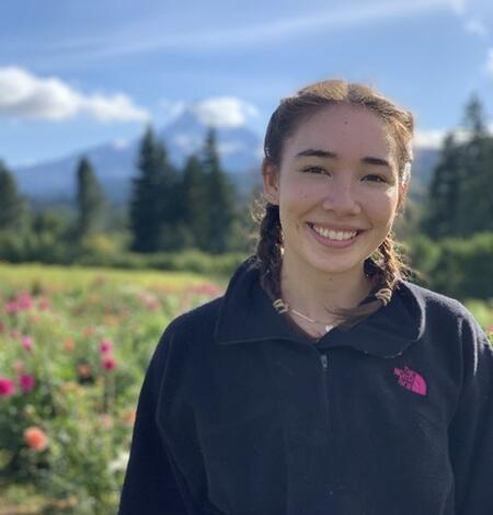 Headshot of a woman smiling in front of a field of flowers and a mountain