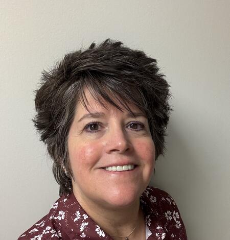 woman with short brown hair and maroon shirt with white flowers