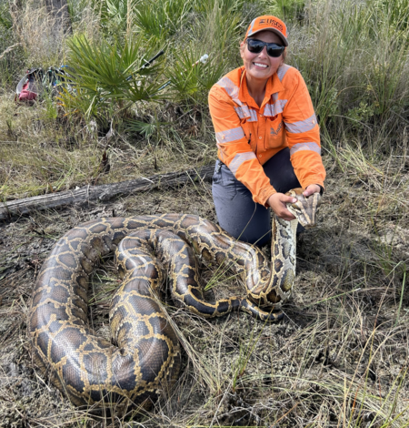 a woman holds a large burmese python