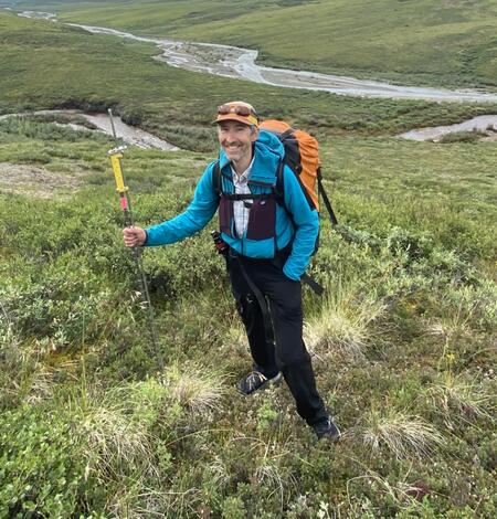 A man in a blue jacket standing in front of a river.