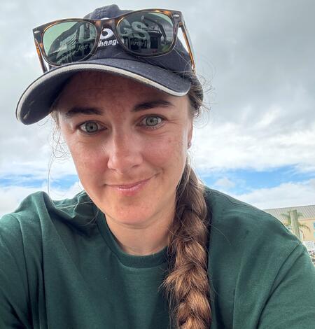 woman in USGS hat and shirt smiling outside