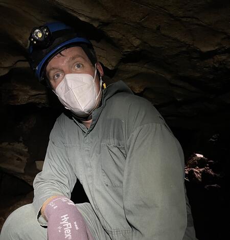 man wearing face mask sits in a cave