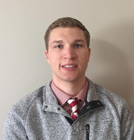 Smiling man standing in front of tan wall