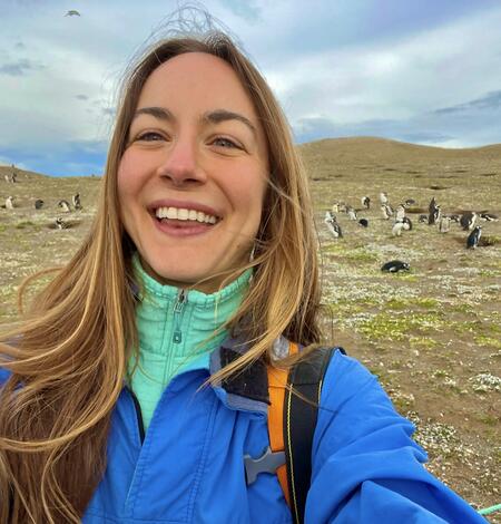 Selfie of bioloigist Seren Bagcilar with a  colony of penguins behind her