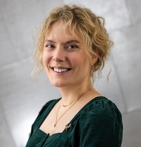 A woman with blonde hair and a green blouse smiles for her picture. 