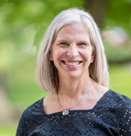 Profile photo for Stacy Curtis, a blonde woman in front of a green forested background.