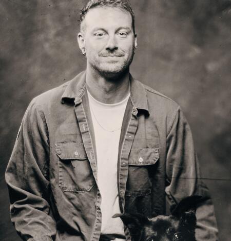 A black and white staff photo of Trevor Faske with his dog