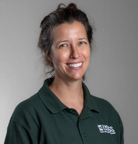 A woman in a green shirt smiling for her picture.