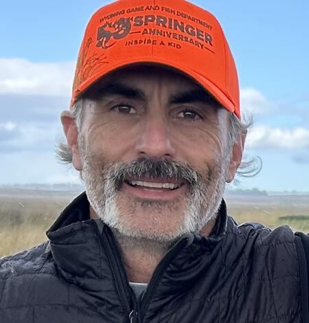 man in an orange hat smiling into camera