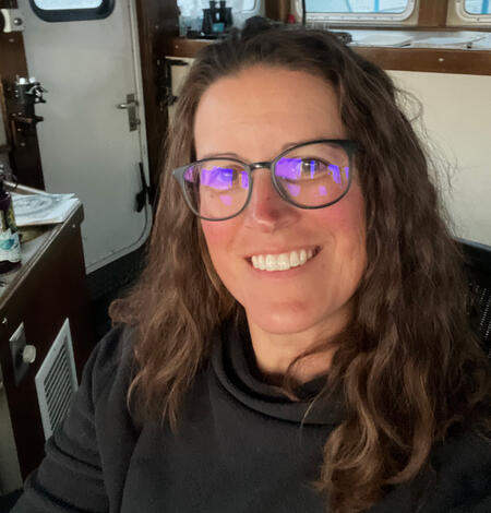 A researcher sitting on the bridge of a large vessel. Lake in the background.