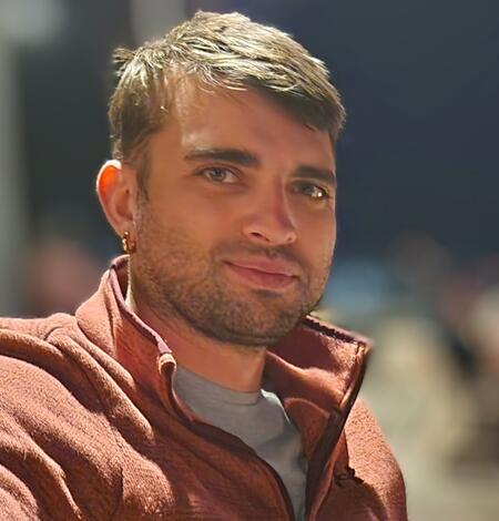 Image of a smiling man in an orange shirt with brown hair