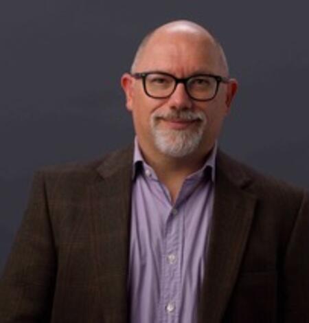 man wearing glasses, purple shirt, and brown blazer