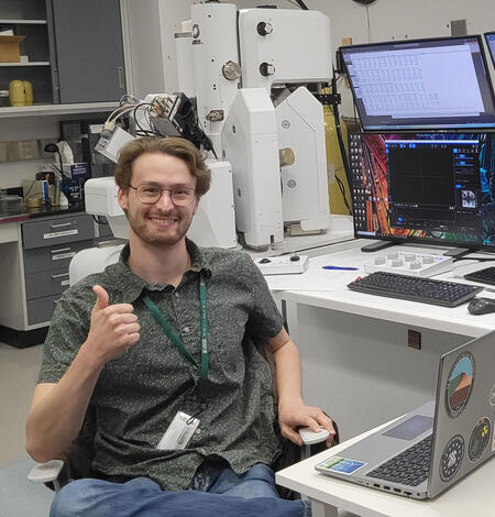 Nicholas E Powell gives a thumbs up while proudly showing off lab equipment