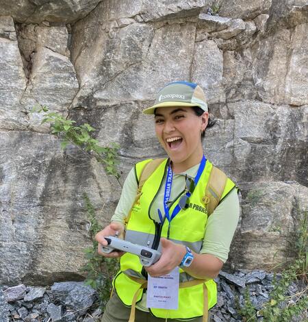 Woman in yellow vest in front of rock