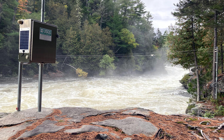 A USGS streamgage mounted in the rocky bank of a raging river