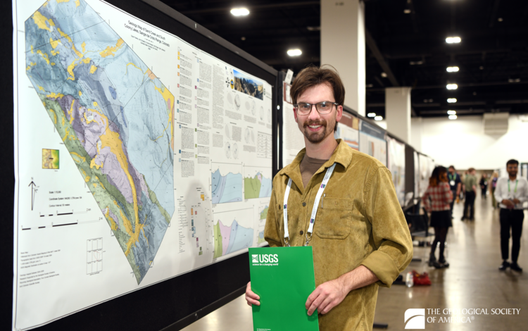 A person stands to the right side of a poster with a colorful geologic map and several cross sections.