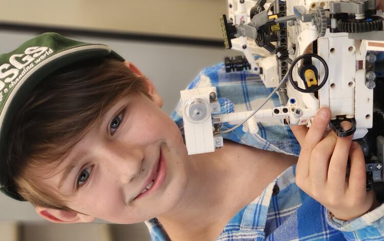 Youth demonstrating a model of the Perseverance Rover that he made using Lego bricks.