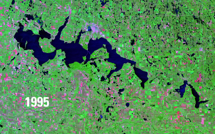 Satellite image showing water bodies in deep blue, green vegetation and pink barren areas